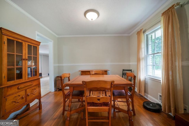 dining area featuring dark wood-type flooring, baseboards, and ornamental molding