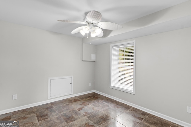 empty room featuring baseboards, ceiling fan, and stone finish flooring