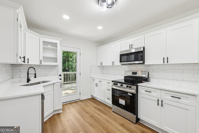 kitchen featuring light wood finished floors, appliances with stainless steel finishes, white cabinetry, and a sink