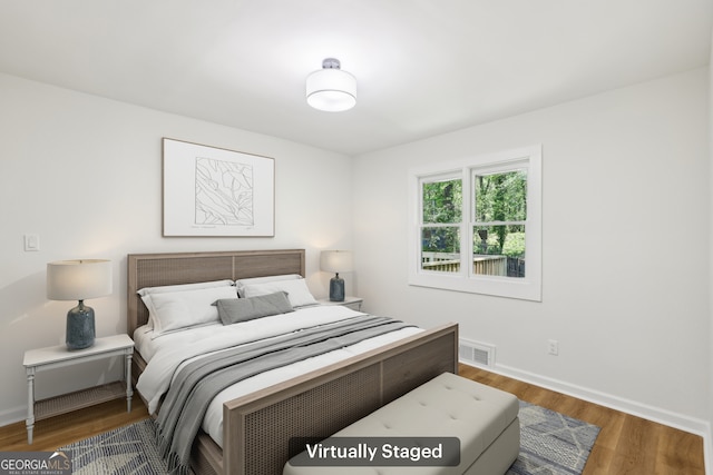 bedroom featuring baseboards, wood finished floors, and visible vents