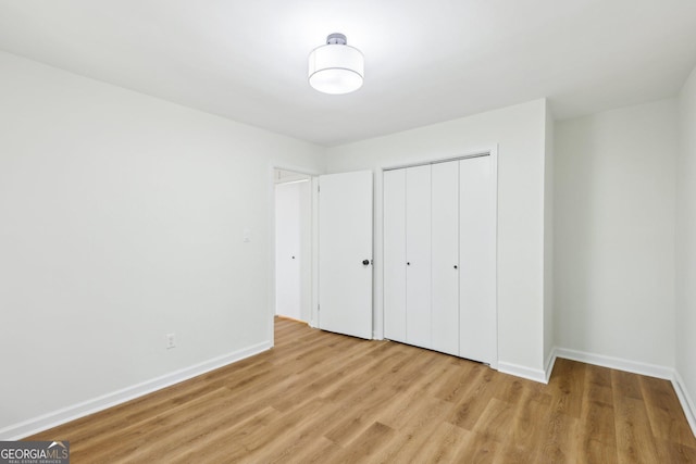 unfurnished bedroom featuring baseboards, a closet, and light wood-style flooring
