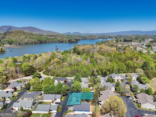 aerial view with a residential view, a view of trees, and a water and mountain view