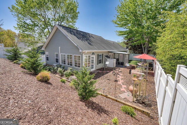 back of house with a shingled roof and a fenced backyard