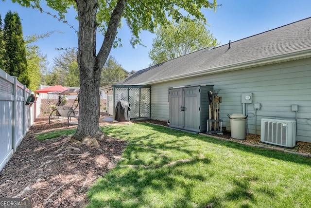 rear view of house with a fenced backyard, roof with shingles, a yard, and cooling unit