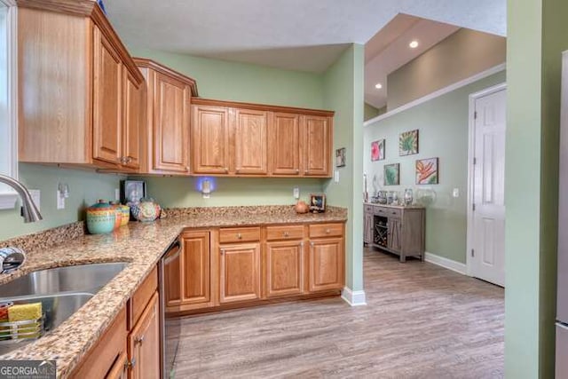kitchen featuring stainless steel dishwasher, a sink, light wood-type flooring, light stone countertops, and recessed lighting