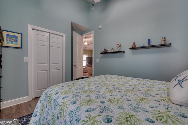 bedroom featuring baseboards, a high ceiling, wood finished floors, and a closet