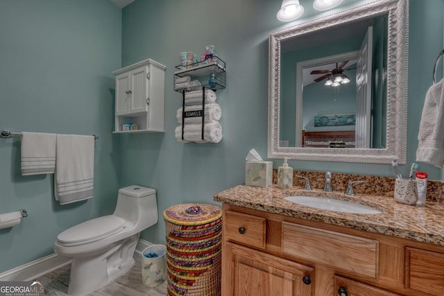 bathroom featuring toilet, a ceiling fan, vanity, and baseboards