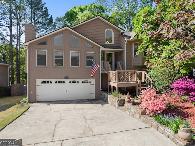 view of front of home with driveway, a chimney, fence, a wooden deck, and an attached garage