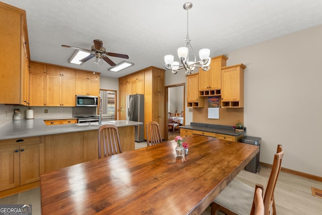 dining room with ceiling fan with notable chandelier, baseboards, a textured ceiling, and light wood finished floors
