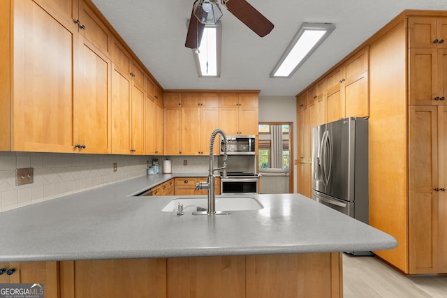 kitchen featuring a peninsula, a ceiling fan, appliances with stainless steel finishes, and tasteful backsplash