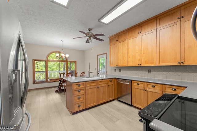 kitchen with a peninsula, light wood-style floors, appliances with stainless steel finishes, and tasteful backsplash