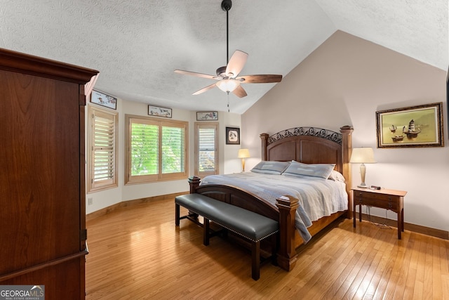 bedroom with vaulted ceiling, baseboards, light wood-style floors, and a textured ceiling