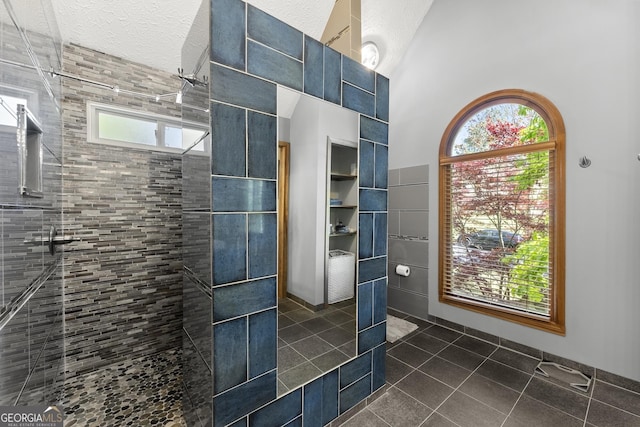 bathroom featuring a high ceiling, tile patterned flooring, a textured ceiling, and a tile shower