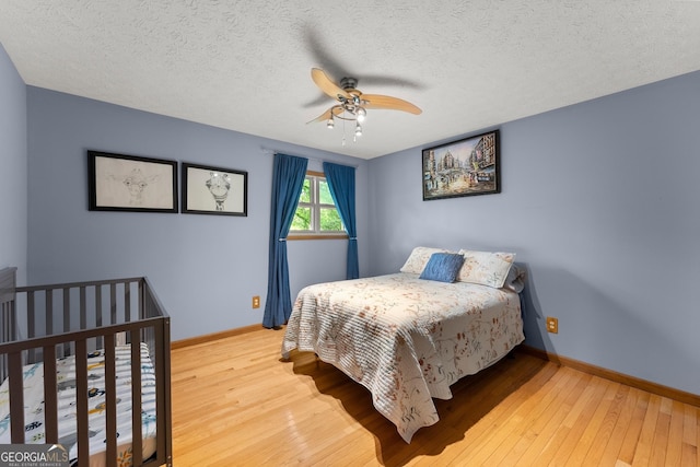 bedroom with baseboards, a textured ceiling, hardwood / wood-style flooring, and ceiling fan