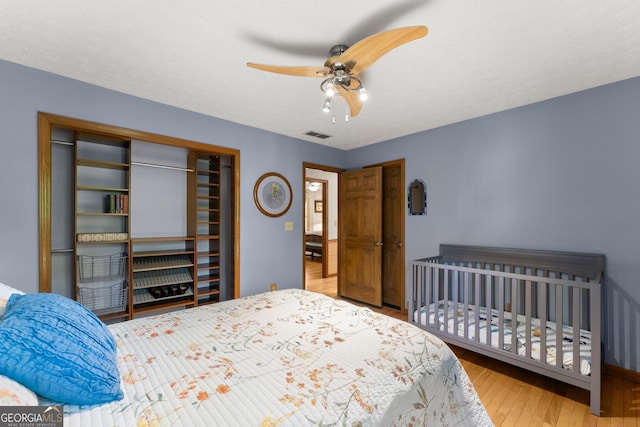 bedroom featuring visible vents, baseboards, a ceiling fan, wood finished floors, and a closet