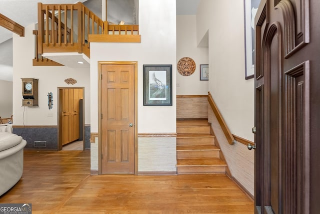 foyer entrance featuring stairway, visible vents, a towering ceiling, and light wood-type flooring