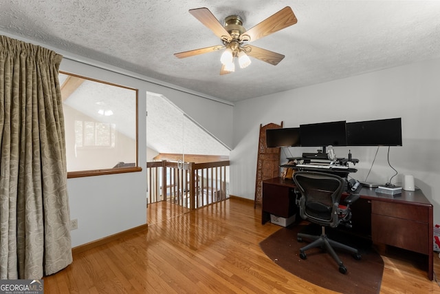 office area with a textured ceiling, vaulted ceiling, baseboards, wood finished floors, and ceiling fan