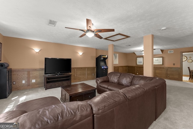 living room featuring wainscoting, ceiling fan, light carpet, and visible vents