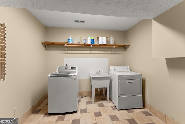 laundry area with separate washer and dryer, laundry area, stone finish flooring, baseboards, and visible vents