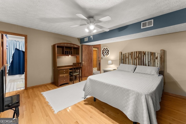 bedroom with light wood finished floors, baseboards, visible vents, a spacious closet, and a closet