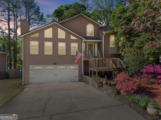 view of front facade featuring a garage, a chimney, concrete driveway, and fence