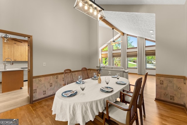 dining space with beamed ceiling, a ceiling fan, and light wood-style flooring
