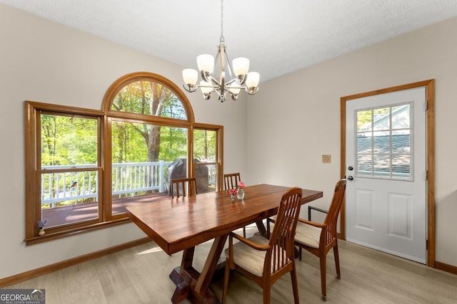 dining area with baseboards, an inviting chandelier, and light wood-style flooring