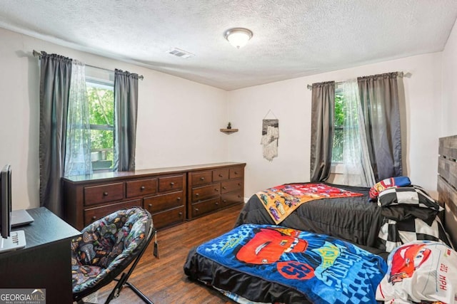 bedroom with visible vents, wood finished floors, and a textured ceiling