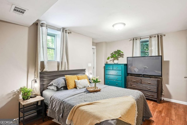 bedroom featuring baseboards, wood finished floors, and visible vents