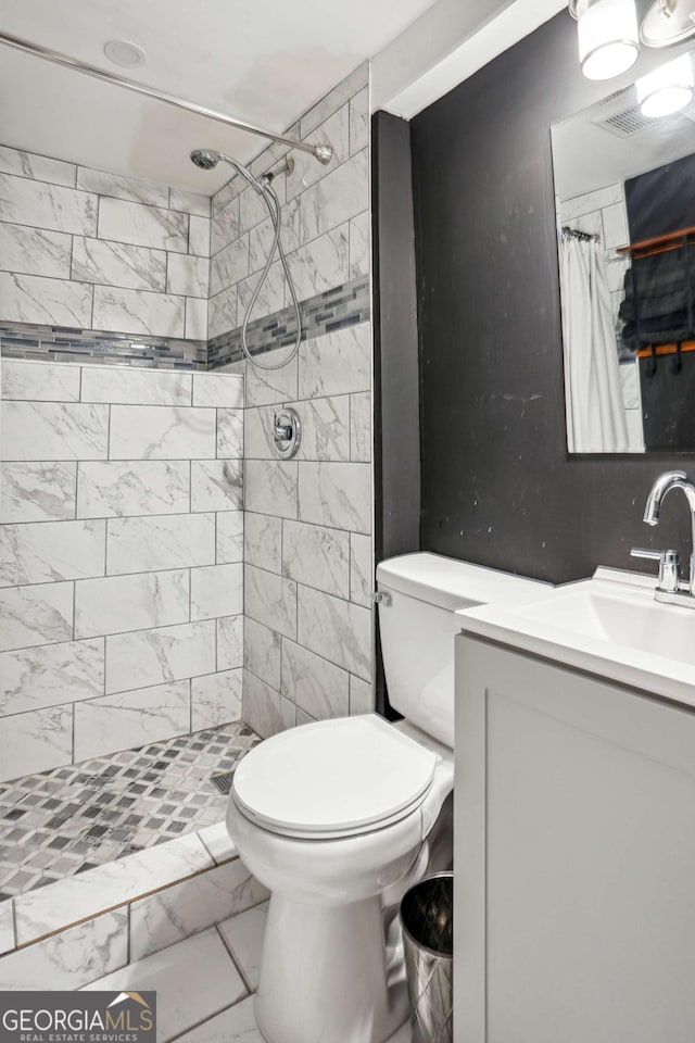 full bath with toilet, marble finish floor, vanity, and a tile shower