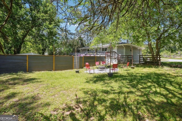 view of yard featuring a fire pit, fence, and a deck