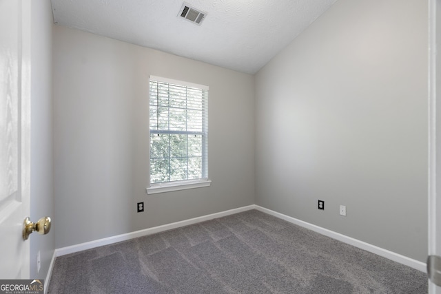 spare room featuring a textured ceiling, dark colored carpet, visible vents, and baseboards
