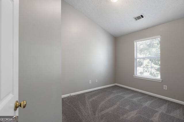 spare room with baseboards, visible vents, a textured ceiling, and dark carpet