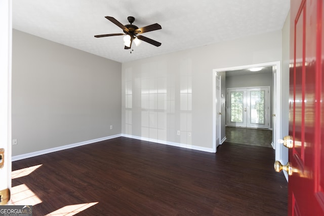 empty room featuring dark wood finished floors, ceiling fan, baseboards, and french doors