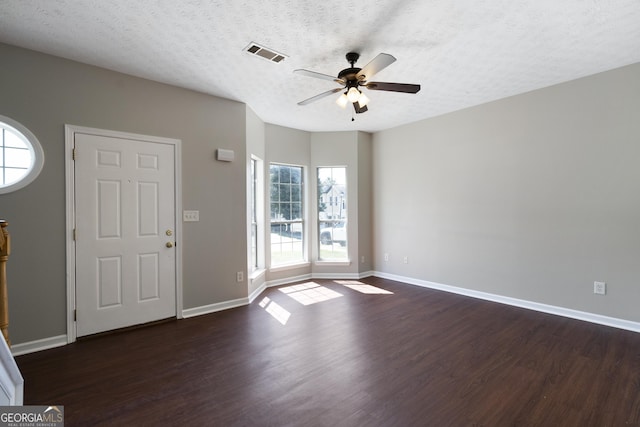 interior space featuring dark wood-style floors, a textured ceiling, baseboards, visible vents, and a ceiling fan