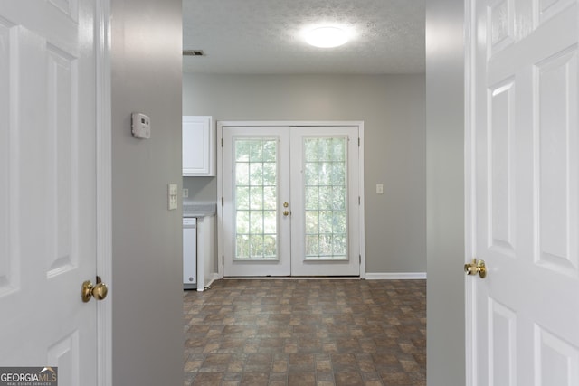 doorway to outside with a textured ceiling, stone finish flooring, baseboards, and french doors