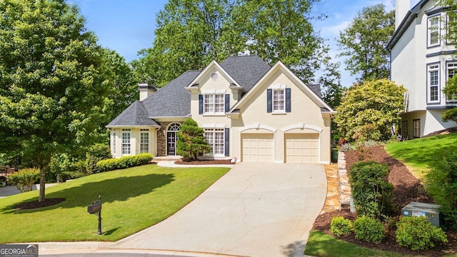 traditional-style house featuring an attached garage, driveway, a chimney, a front lawn, and stucco siding