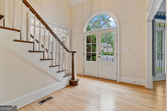 foyer with wood finished floors, stairs, baseboards, and high vaulted ceiling