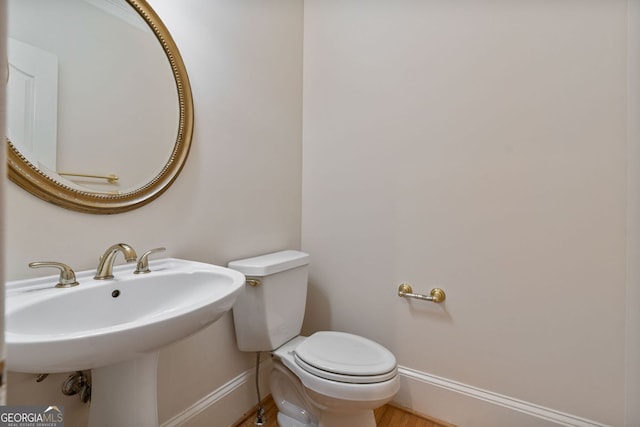 bathroom featuring baseboards, toilet, and a sink