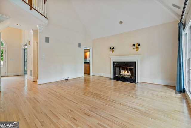 unfurnished living room with high vaulted ceiling, light wood-type flooring, a premium fireplace, and baseboards