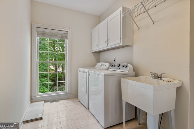 clothes washing area with cabinet space, washing machine and dryer, light tile patterned flooring, and baseboards
