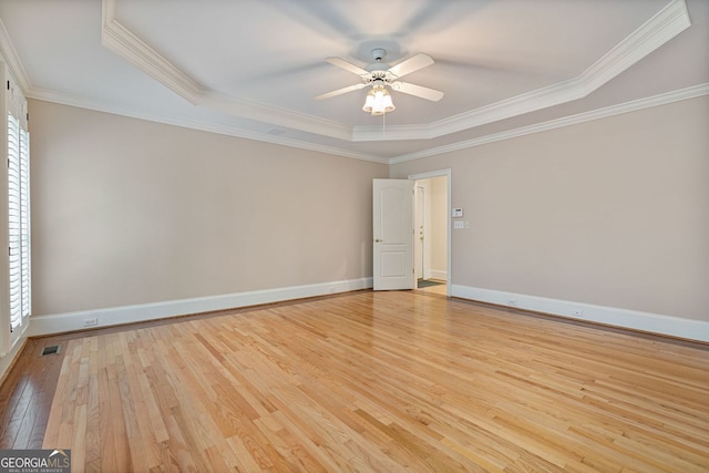 unfurnished room with light wood-type flooring, a tray ceiling, ceiling fan, baseboards, and ornamental molding