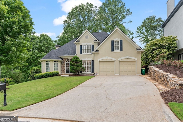 traditional-style home with a garage, concrete driveway, a front lawn, stucco siding, and a shingled roof