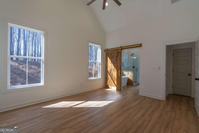 1250 Hayes Mill Rd, Carrollton, GA 30117 - unfurnished bedroom with a barn door, high vaulted ceiling, wood finished floors, and a ceiling fan
