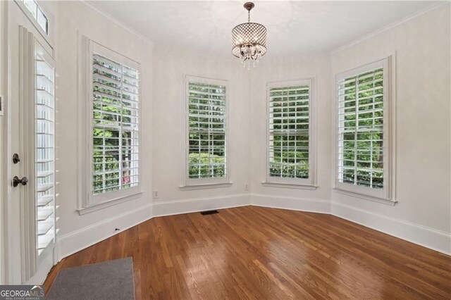 3115 Corsair Curv, Cumming, GA 30040 - unfurnished dining area with baseboards, wood finished floors, a chandelier, ornamental molding, and healthy amount of natural light