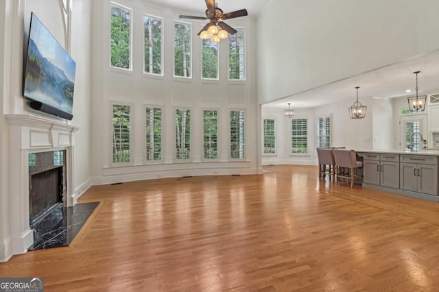3115 Corsair Curv, Cumming, GA 30040 - living room featuring a towering ceiling, a fireplace, wood finished floors, a ceiling fan, and a chandelier