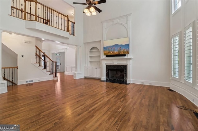 3115 Corsair Curv, Cumming, GA 30040 - unfurnished living room with a towering ceiling, built in features, ceiling fan, wood finished floors, and stairway