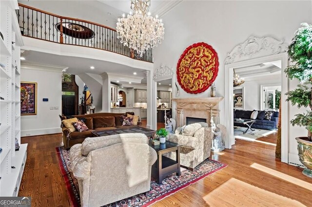 2120 Blackheath Trce, Alpharetta, GA 30005 - living area with wood finished floors, crown molding, a fireplace, a chandelier, and a high ceiling