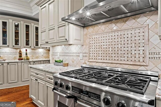 2120 Blackheath Trce, Alpharetta, GA 30005 - kitchen featuring high end stainless steel range, wall chimney exhaust hood, decorative backsplash, glass insert cabinets, and wood finished floors