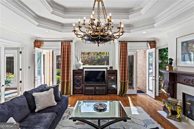 2120 Blackheath Trce, Alpharetta, GA 30005 - living room featuring wood finished floors, a chandelier, crown molding, a raised ceiling, and a fireplace